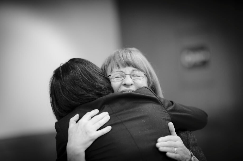 Volunteers embracing warmly at a community meeting